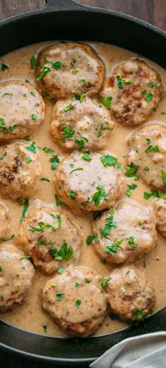 a pan filled with meatballs covered in gravy and garnished with parsley