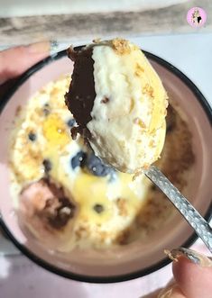 a person is eating ice cream with chocolate and blueberries on it in a bowl