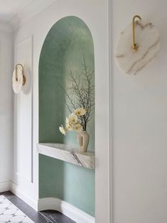 a vase with yellow flowers on a shelf in a white walled entryway to a home