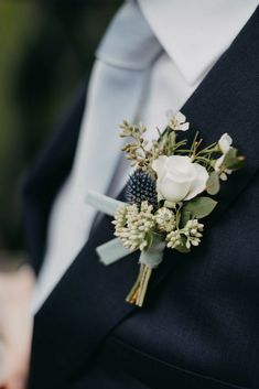 a man in a suit and tie wearing a boutonniere with flowers on it