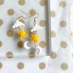 a pair of earrings with stars and moon on them sitting on a polka dot tablecloth