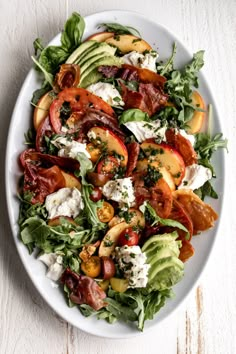 a salad with tomatoes, lettuce and bacon on it in a white bowl