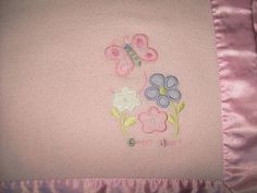 a close up of a pink blanket with flowers and a butterfly on the back of it