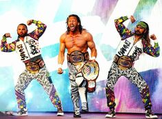 three men in wrestling gear standing on stage