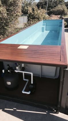 an above ground swimming pool in the middle of a building with a wooden deck and metal piping