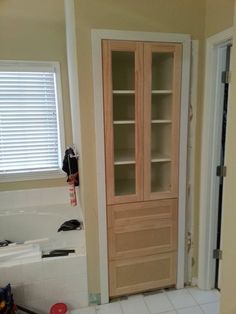 an empty bathroom with a wooden cabinet in the middle and tile flooring on the other side