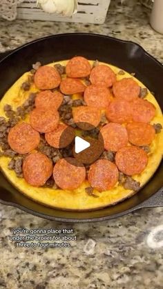 a pizza with pepperoni and sausage in a skillet on a kitchen counter top