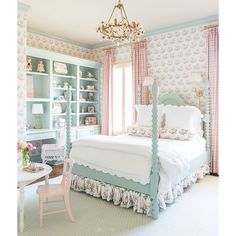 a white bed sitting in a bedroom next to a pink and blue book shelf filled with books