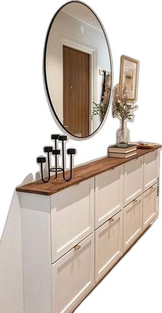 a mirror and some white cabinets with drawers on top of each other in front of a wall