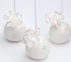 three white cake pops with silver decorations on them