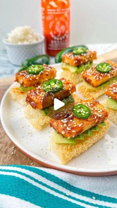 some food is on a white plate with green peppers and sauces next to it