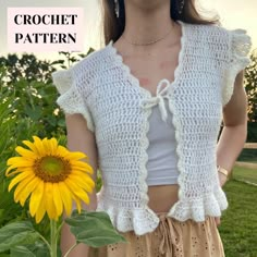 a woman standing in front of a sunflower wearing a white crochet top