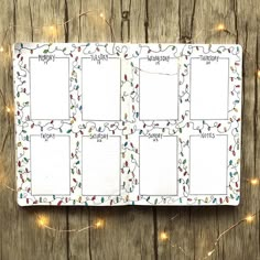 an open planner with christmas lights around it on a wooden table next to string lights