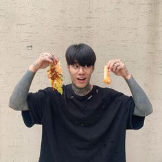 a young man holding two pieces of pizza in front of his face with both hands