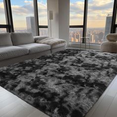 a living room with large windows and a rug on the floor in front of it