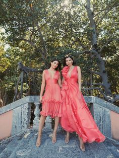 two women in dresses standing on steps near trees