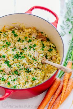 a red pot filled with rice and carrots on top of a white countertop