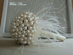 a white brooch with pearls and feathers in it's center, sitting on a table