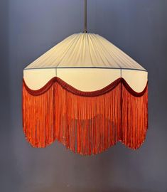 a lamp shade with fringes hanging from it's side on a gray wall