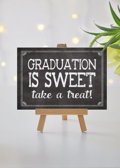 a chalkboard sign that says graduation is sweet take a treat next to a potted plant