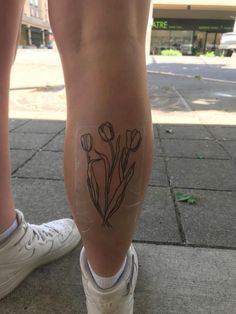 a woman's legs with tattoos on them and flowers drawn on the side of her leg