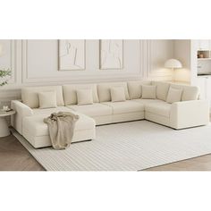 a living room with a large white sectional couch and rugs on the floor in front of it