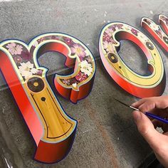 a person is painting the letters with paintbrushes