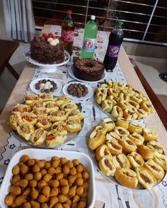 a table topped with lots of desserts and pastries next to bottles of soda