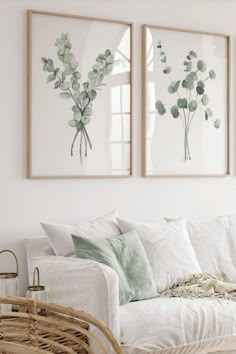 two framed pictures hang on the wall above a white couch in a living room with wicker furniture