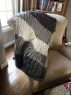 a couch with a blanket on top of it in front of a bookshelf