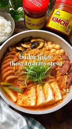 a bowl filled with noodles and meats next to other foods on top of a wooden table