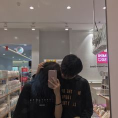 two people standing in front of a store looking at their cell phones