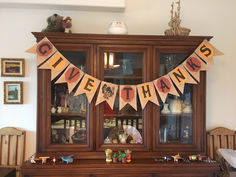 an old china cabinet decorated for thanksgiving with bunting and decorations on the top shelf