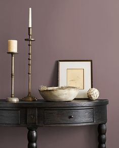 a table with a bowl and two candles on it next to a framed photograph, candle holder and other items