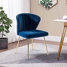 a blue chair sitting in front of a white table with a plant on top of it