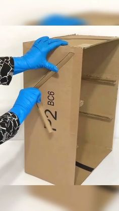 a person in blue gloves is opening a cardboard box with the number twenty on it