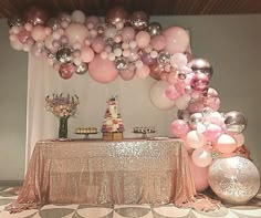 a table topped with lots of pink and white balloons