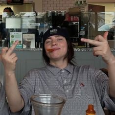 a woman sitting at a table holding up two fingers