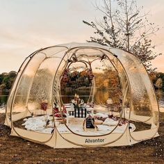 an outdoor tent set up on the ground with chairs and tables in front of it