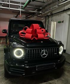 a black mercedes with a red bow on it's hood