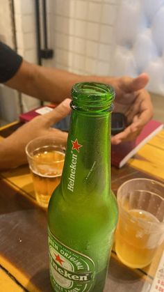 a green beer bottle sitting on top of a wooden table