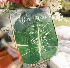 a sign that says bar menu next to some flowers and other items on a table