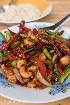 a bowl filled with shrimp and vegetables on top of a wooden table next to rice