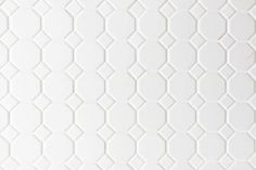 a close up view of a white tile wall with an interesting pattern on the surface