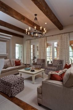 a living room filled with furniture and a chandelier hanging from the ceiling over a fire place