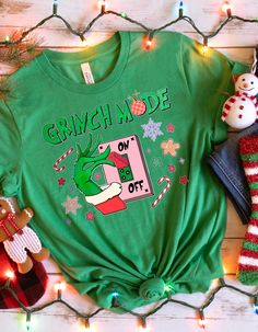 GRINCH MODE SHIRT - "Grinch Mode On Switch" Tee Get into the Grinch spirit with our "Grinch Mode On Switch" shirt! Perfect for spreading holiday cheer with a humorous twist, this tee is a fun addition to any Christmas wardrobe. Ideal for family gatherings or as a playful gift for the Grinch fan in your life. Product Features: Material: Crafted from 100% cotton for a soft, breathable feel. Sport Grey is a blend of 90% cotton and 10% polyester, Ash Grey has 99% cotton and 1% polyester, and Heather colors are a 50/50 blend of cotton and polyester. Fabric Weight: 5.0-5.3 oz/yd² (170-180 g/m offering a substantial yet comfortable feel. Fit: The unisex classic fit provides a structured look that pairs well with layered streetwear or casual outfits. Construction: Includes open-end yarn, tubular f Grinchmas Tshirt, Switch Shirt, Funny Grinch, Der Grinch, Grinch T Shirt, Grinch Shirt, Christmas Wardrobe, Grinch Shirts, Family Christmas Shirts