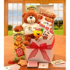 a teddy bear sitting in a gift box with cards and candies on the table