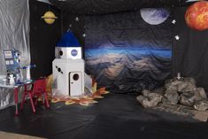 a space themed room with a rocket ship and other items on the floor in front of it