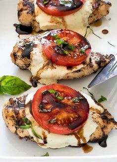 grilled chicken with tomatoes and mozzarella sauce on a white plate next to a knife