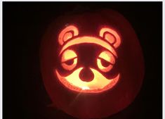 a close up of a carved pumpkin with a raccoon face in the center